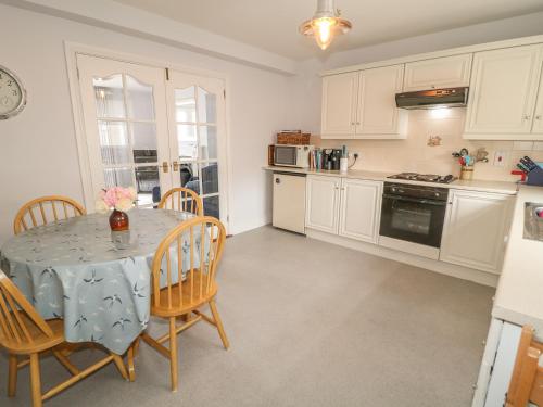 a kitchen with a table and chairs and a kitchen with white cabinets at 1 The Moorings in Newry