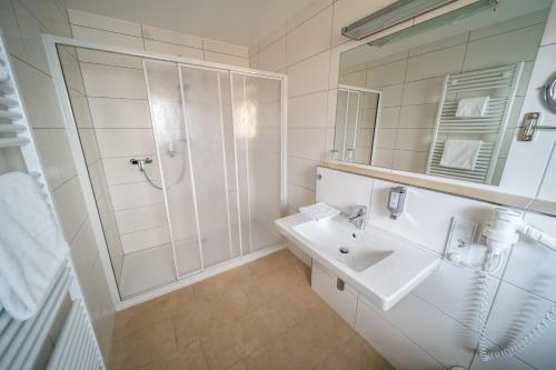 a white bathroom with a shower and a sink at Hotel Rieder in Wiesemscheid