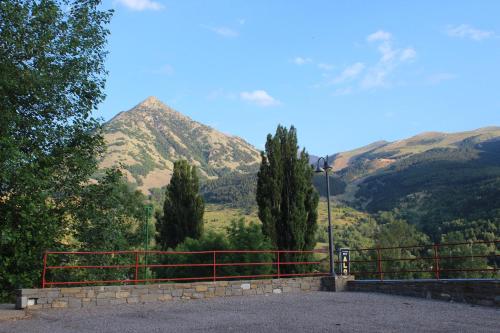a red fence with a mountain in the background at Hotel SNO Edelweiss in Cerler