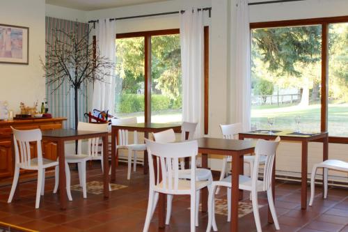 un comedor con sillas blancas, mesas y ventanas en Hotel SNO Edelweiss, en Cerler