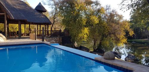 a swimming pool with a gazebo next to a pond at River Rock Lodge in Parys