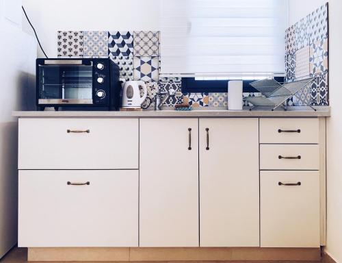 a kitchen with white cabinets and a microwave at HaBaitBe Matityahu By Domus in Beer Sheva