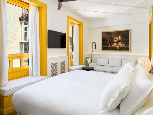 a bedroom with a white bed and a couch at H10 Casa de la Plata in Seville