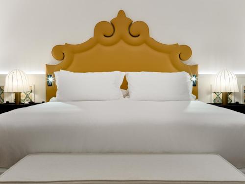 a large white bed with a large headboard at H10 Casa de la Plata in Seville