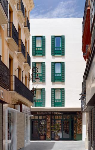an apartment building with green and white windows at H10 Casa de la Plata in Seville