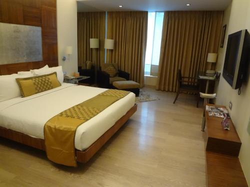a hotel room with a large bed and a living room at Mirage Hotel, Mumbai International Airport in Mumbai
