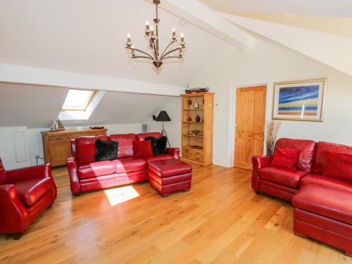a living room with red leather furniture and a chandelier at Villa Marina in Barrow in Furness