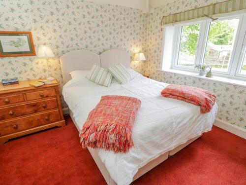 a bedroom with a white bed with a dresser and a window at Manor Cottage in Pickering