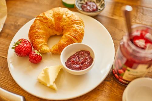 a plate of food with a croissant and jam and strawberries at Rochter Landhotel in Zeltingen-Rachtig