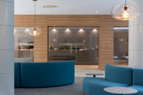 a lobby with blue chairs and tables and a kitchen at Hotel Macià Sevilla Kubb in Seville