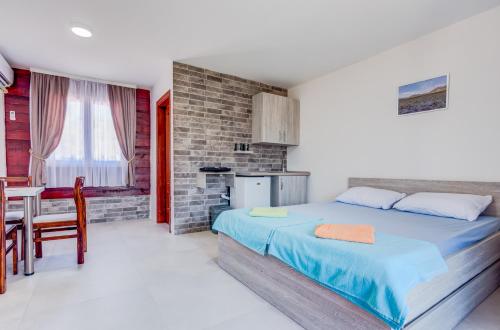 a bedroom with a bed and a table and a kitchen at Apartments Obala in Podgorica
