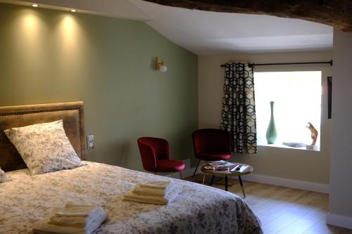 um quarto com uma cama com 2 cadeiras e uma janela em La maison du sculpteur em Tiffauges