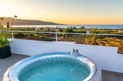 a bath tub on a balcony with a view of the ocean at Louladakis Apartments in Kolymvari