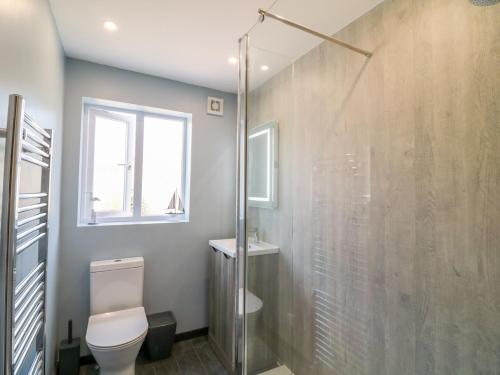 a bathroom with a toilet and a glass shower at Meadow View Cottage in Exmouth