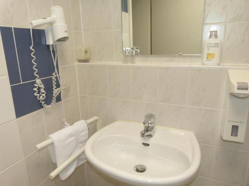 Baño blanco con lavabo y espejo en Hotel Trebeltal, en Demmin