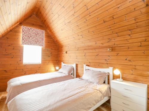 two beds in a room with wooden walls at Avonside Cottage in Bristol