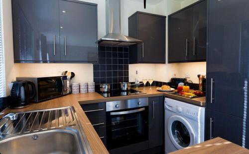 a kitchen with black cabinets and a sink and a dishwasher at Valley Lodge in Trearddur