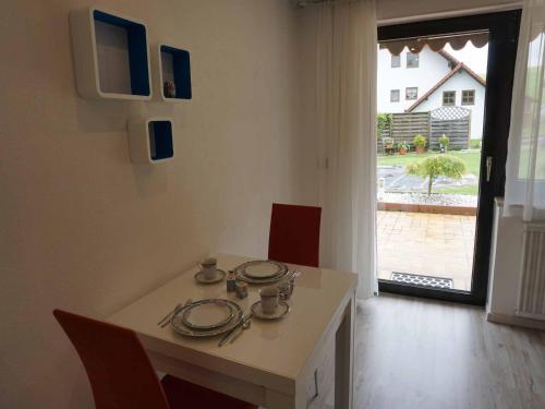 mesa de comedor con platos y ventana en Ferienwohnung Piller 4 Sterne en Michelsneukirchen