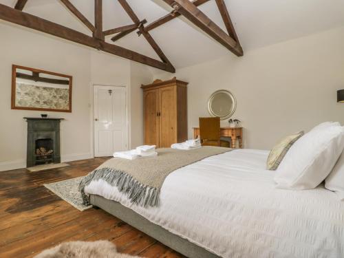 a bedroom with a large white bed and a fireplace at Warren House Cottage in Market Rasen