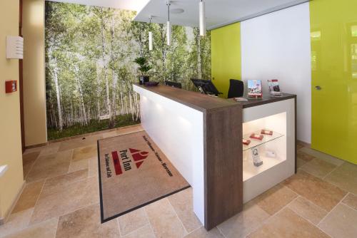 an office with a reception desk with a tree mural at Port Inn Hotel in Eichwalde