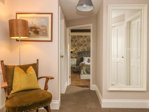 a hallway with a chair with a yellow pillow on it at Warren House Cottage in Market Rasen