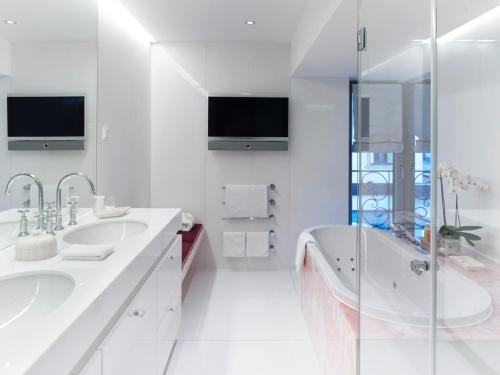 a white bathroom with two sinks and a tub at A-ROSA Hotel Thurnher's Alpenhof in Zürs am Arlberg