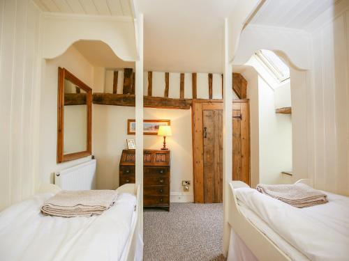 a bedroom with two bunk beds and a mirror at Murton Cottage in Burford