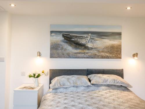 a bedroom with a bed and a painting of a boat at Cuckoo Cottage in Bridport