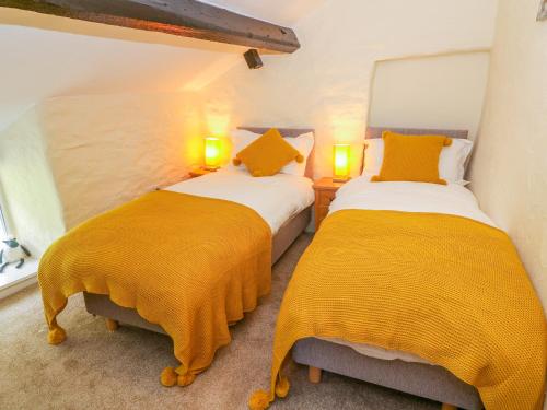 2 Betten in einem Zimmer mit gelben Decken in der Unterkunft Tilberthwaite Farm Cottage in Coniston