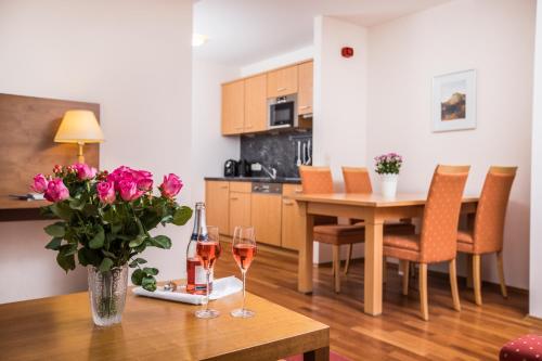 a table with two glasses of wine and a vase of flowers at Hotel am See - Seeresidenz in Altaussee