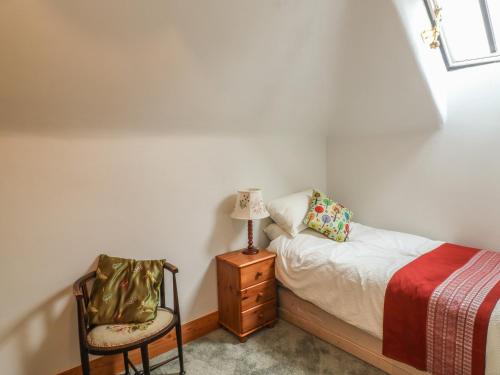 a small bedroom with a bed and a chair at The Old Laundry in North Tawton