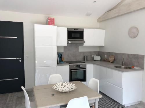 a kitchen with white cabinets and a table with chairs at Guesthouse proche bordeaux Parking in Eysines