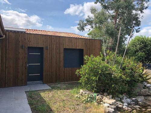 a wooden building with two garage doors on it at Guesthouse proche bordeaux Parking in Eysines