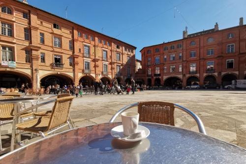 a table with a cup of coffee on it in a courtyard at Le bon'appart - 50m de la cathédrale in Montauban