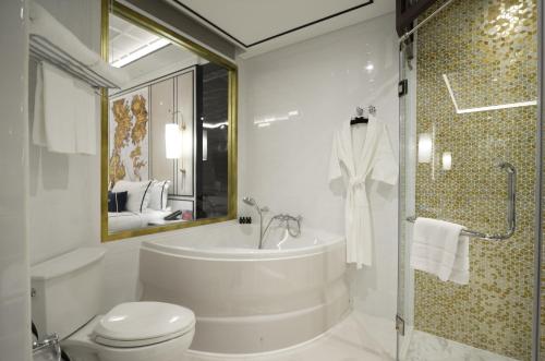 a bathroom with a tub and a toilet and a sink at Mövenpick Myth Hotel Patong Phuket in Patong Beach