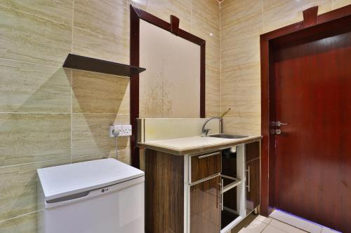 ein kleines Bad mit einem Waschbecken und einer Tür in der Unterkunft OYO 273 Star Yanbu Hotel Suites in Yanbu
