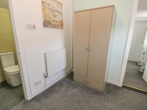 une salle de bain avec une armoire et des toilettes à l'intérieur dans l'établissement Falconers Cottage, à Holyhead