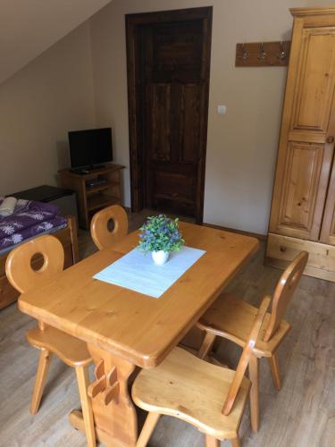 a wooden table and chairs with a plant on it at Pokoje U Moniki in Grywałd