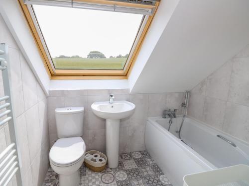 a bathroom with a toilet and a sink and a window at 5 Yarmouth Cottages in Freshwater