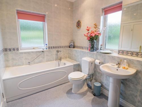 a bathroom with a tub and a toilet and a sink at Sevenacres in Kelso