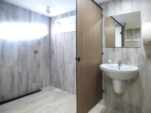 a bathroom with a sink and a shower with a mirror at Hazel Cottage in Bude
