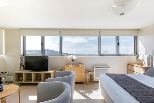 um quarto com uma cama e uma televisão e algumas janelas em GB Athens View Luxury Suite em Atenas