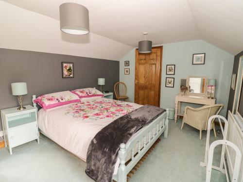 a bedroom with a large bed and a desk at Cottage on the Common in Westbury on Severn