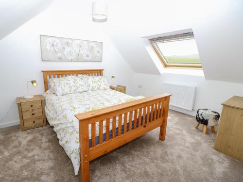 a bedroom with a wooden bed and a window at 5 Yarmouth Cottages in Freshwater