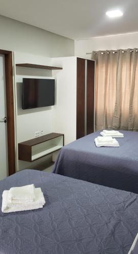 a hotel room with two beds and a flat screen tv at Flats Grangeiro in Crato