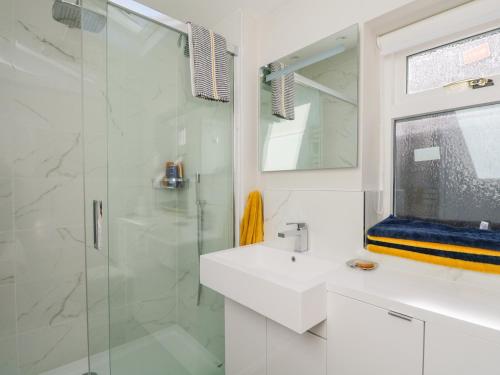 a white bathroom with a sink and a shower at 36 Sandend Village in Banff