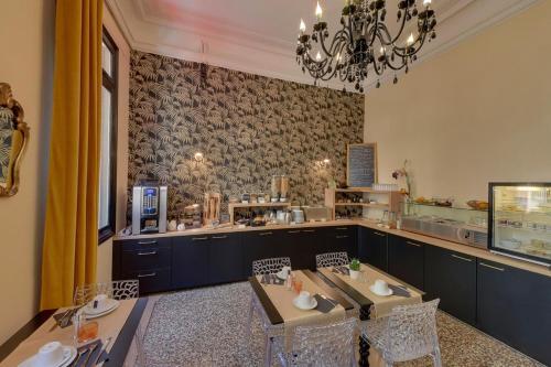 a restaurant with tables and chairs and a chandelier at Hôtel La Résidence in Narbonne