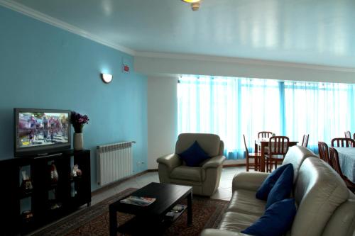 a living room with a couch and chairs and a television at Residencial Stª Joana in Aveiro