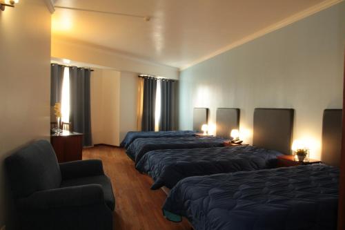 una habitación de hotel con 4 camas y una silla en Residencial Stª Joana, en Aveiro