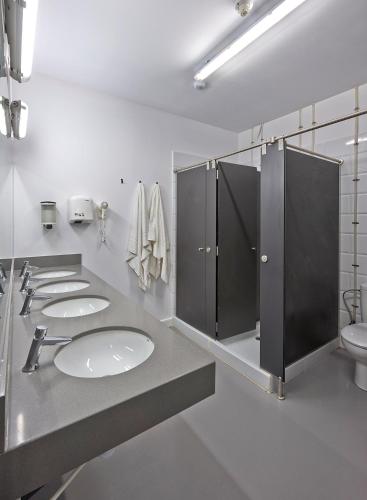 a bathroom with three sinks and stalls in it at Hola Hostal Collblanc in Hospitalet de Llobregat